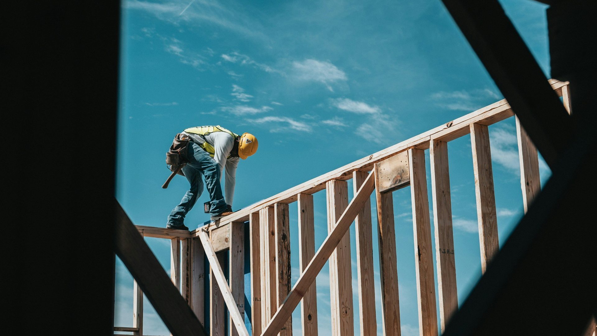 man in yellow shirt and blue denim jeans jumping on brown wooden railings under blue and